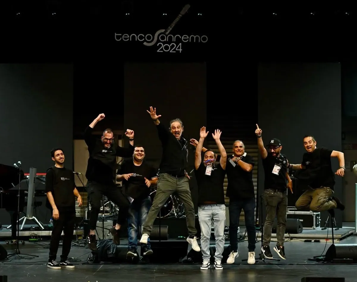 La squadra di Blur che salta di gioia sul palco del Premio Tenco